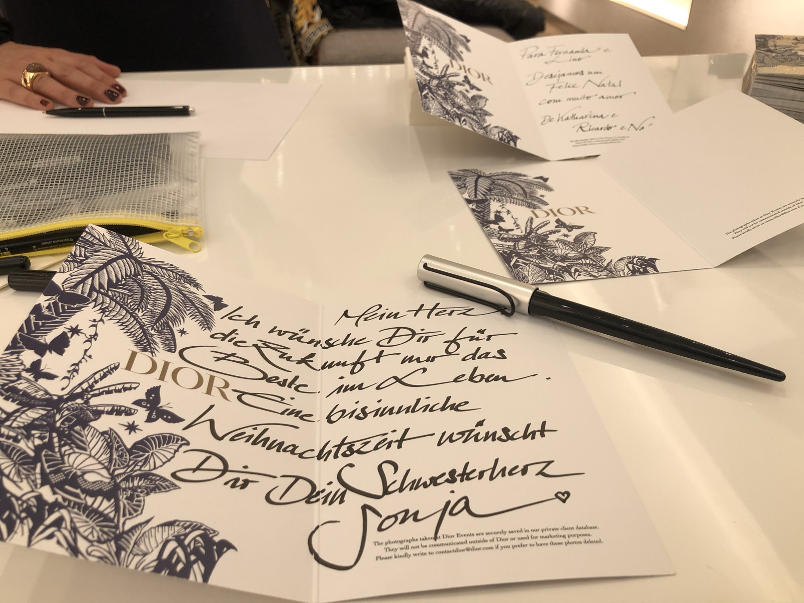 Aufgeklappte Dior-Weihnachtskarte mit handgeschriebenem Gruß, daneben weitere Karten und ein Stift