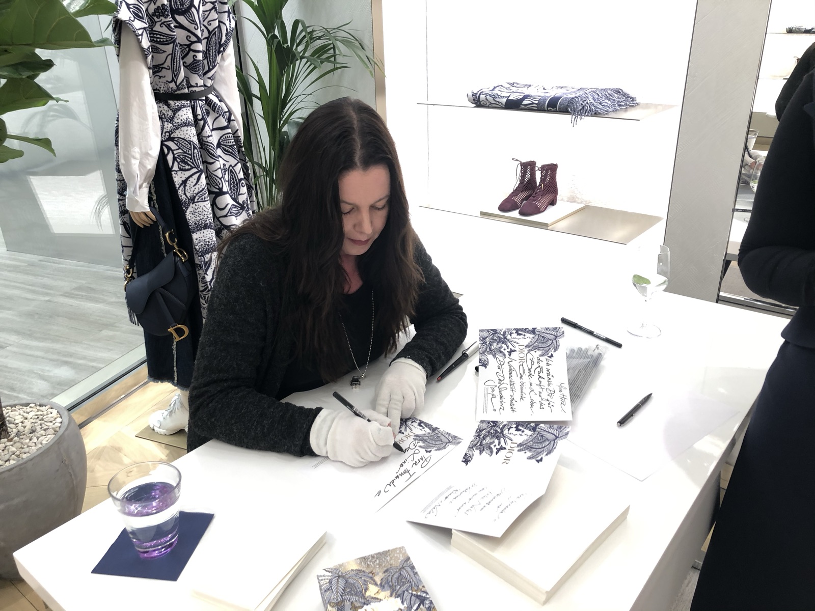 Michaela Al-Badri schreibt mit weißen Handschuhen Karten in einer Dior-Boutique